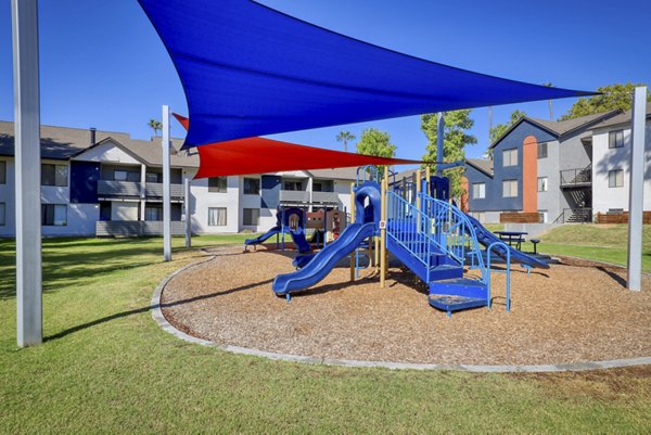Playground with slides and swings at The Julia Apartments, a family-friendly amenity perfect for children to enjoy outdoor play