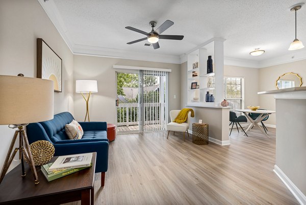 Modern living room with large windows at Mariners Crossing Apartments, featuring comfortable seating and stylish decor
