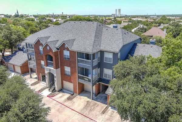 â€œModern brick and siding luxury apartments surrounded by trees in an inviting community settingâ€