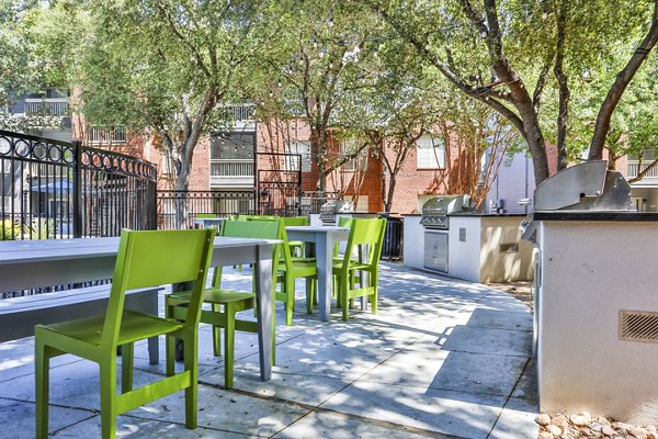 Outdoor grill area with seating at The Quarry Alamo Heights Apartments, perfect for social gatherings and BBQs