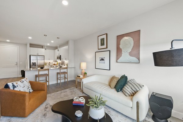 Living room featuring modern decor and large windows at Alexan Montview Plaza Apartments