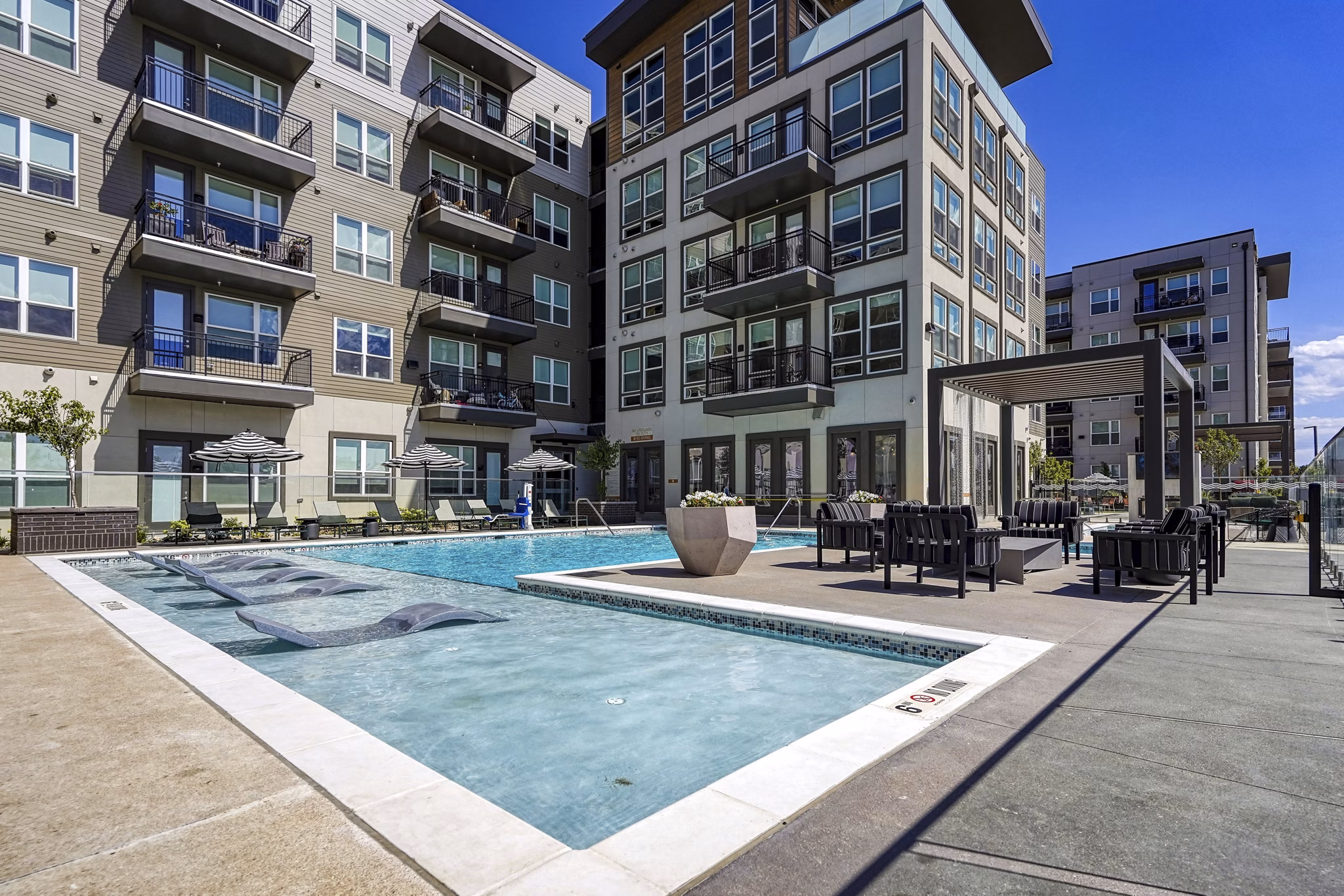 Luxury poolside relaxation at Alexan Montview Plaza Apartments, featuring sun loungers and landscaped surroundings