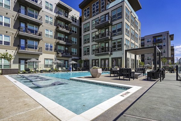 Luxury poolside relaxation at Alexan Montview Plaza Apartments, featuring sun loungers and landscaped surroundings