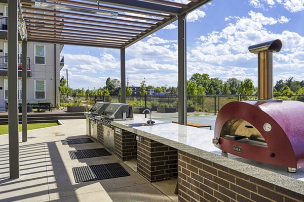 Outdoor grill area with seating at Alexan Montview Plaza Apartments