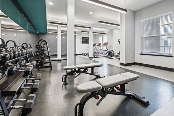 State-of-the-art fitness center at Apex Marathon Village Apartments, offering cardio machines and weights for residents