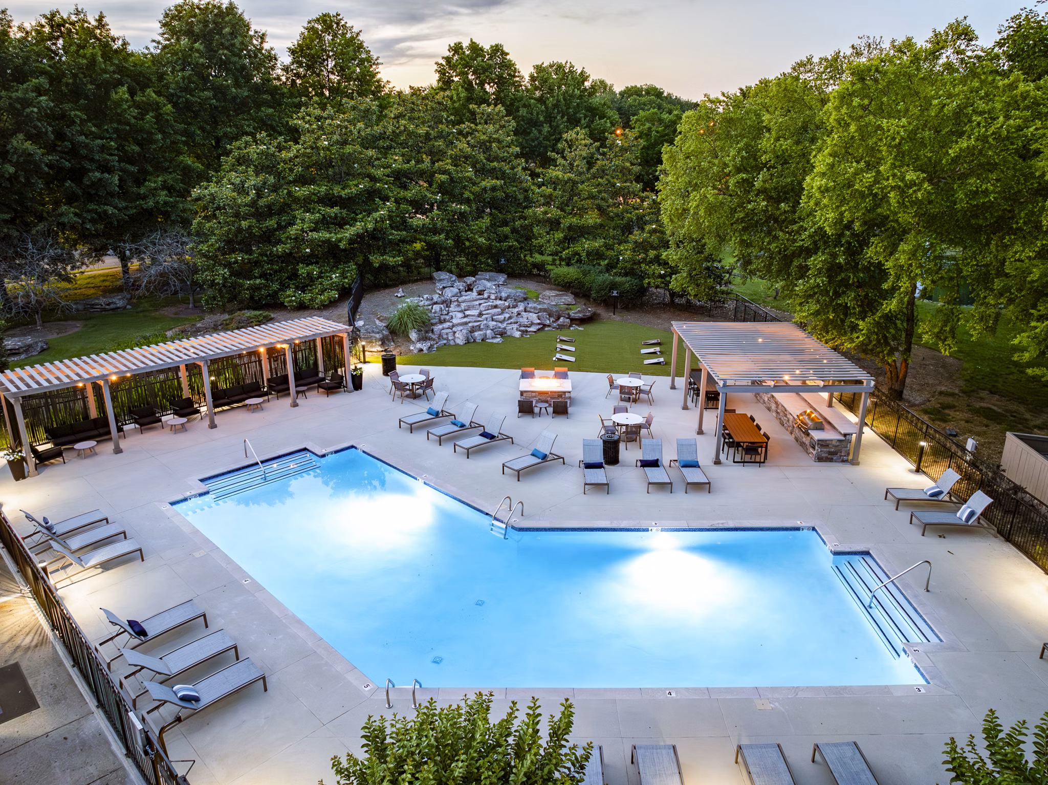 Modern outdoor pool area at Ashton Brook Apartments featuring lush landscaping and lounge chairs for relaxation