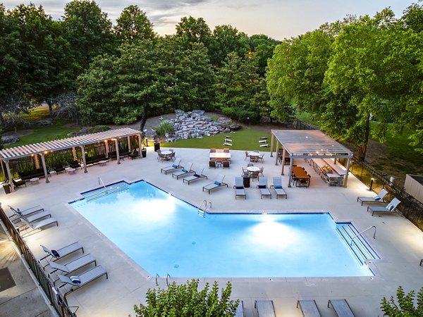 Modern outdoor pool area at Ashton Brook Apartments featuring lush landscaping and lounge chairs for relaxation