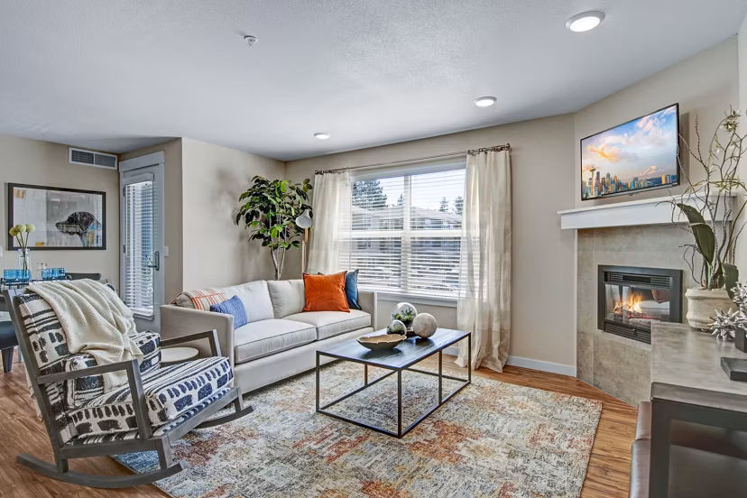 Spacious living room with modern furnishings and large window at Seasons at Farmington Reserve Apartments Perfect for stylish luxury living