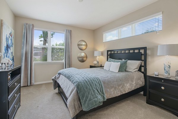 Bedroom with modern decor and large windows at Integra Lakes Apartments