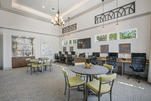 Modern office workspace with tables, chairs, and computers, featuring a decorative chandelier