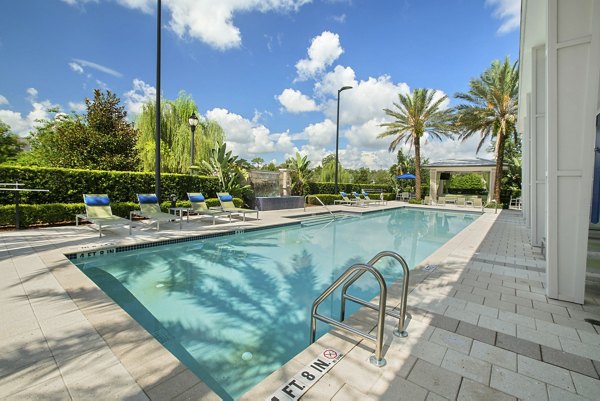 Outdoor swimming pool with lounge chairs and palm trees at luxury apartments