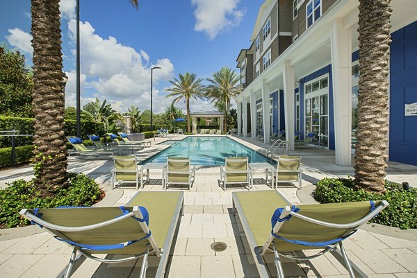 Resort-style swimming pool with lounge chairs and palm trees at luxury apartments