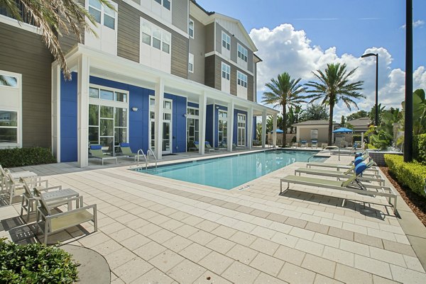 Outdoor swimming pool area with lounge chairs and luxury apartments in the background