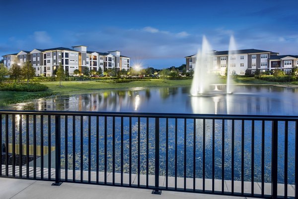 Luxury residential complex featuring a serene pond with fountains and elegant landscaping