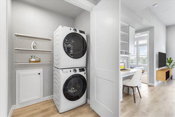 Home office with built-in desk and adjacent laundry room at The Ludlow Apartments