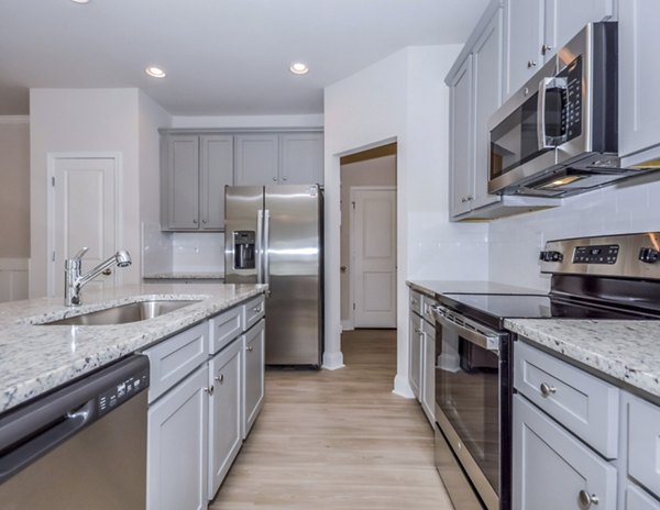 Modern kitchen featuring sleek countertops and stainless steel appliances in Tranquil Gardens Apartments