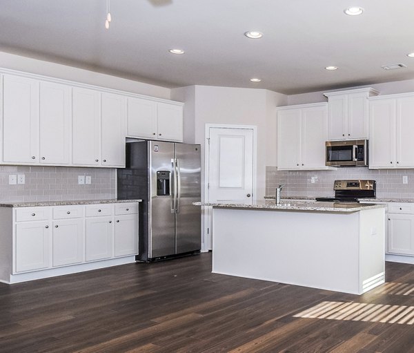Modern kitchen with stainless steel appliances and granite countertops at Tranquil Gardens Apartments