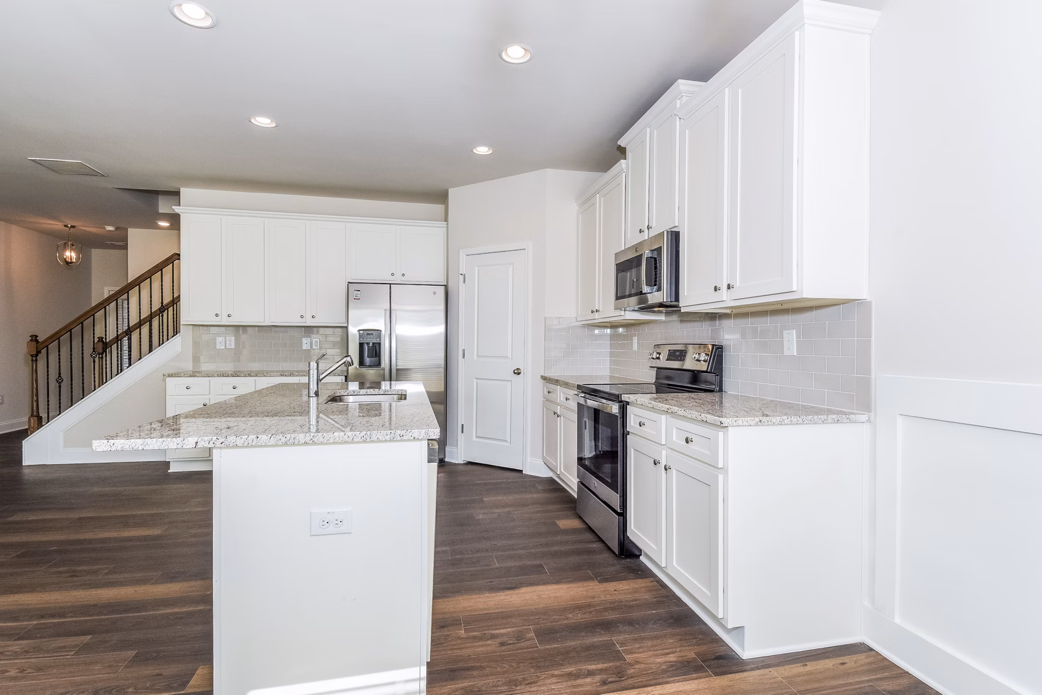 Modern kitchen with stainless steel appliances and quartz countertops in Tranquil Gardens Homes luxury apartments