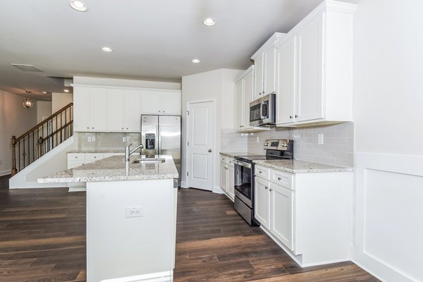 Modern kitchen with stainless steel appliances and quartz countertops in Tranquil Gardens Homes luxury apartments