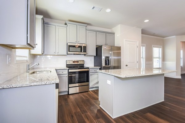 Modern kitchen featuring stainless steel appliances and granite countertops at Tranquil Gardens Homes luxury apartments