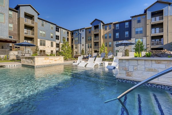 Resort-style pool at Alders Magnolia Apartments with lush landscaping and lounge seating