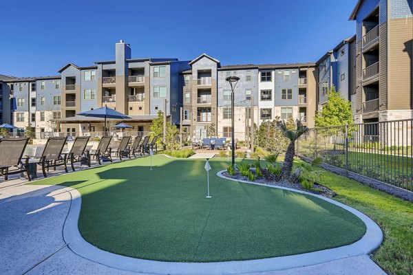 Putting green at Alders Magnolia Apartments: Luxurious golfing amenity surrounded by lush gardens