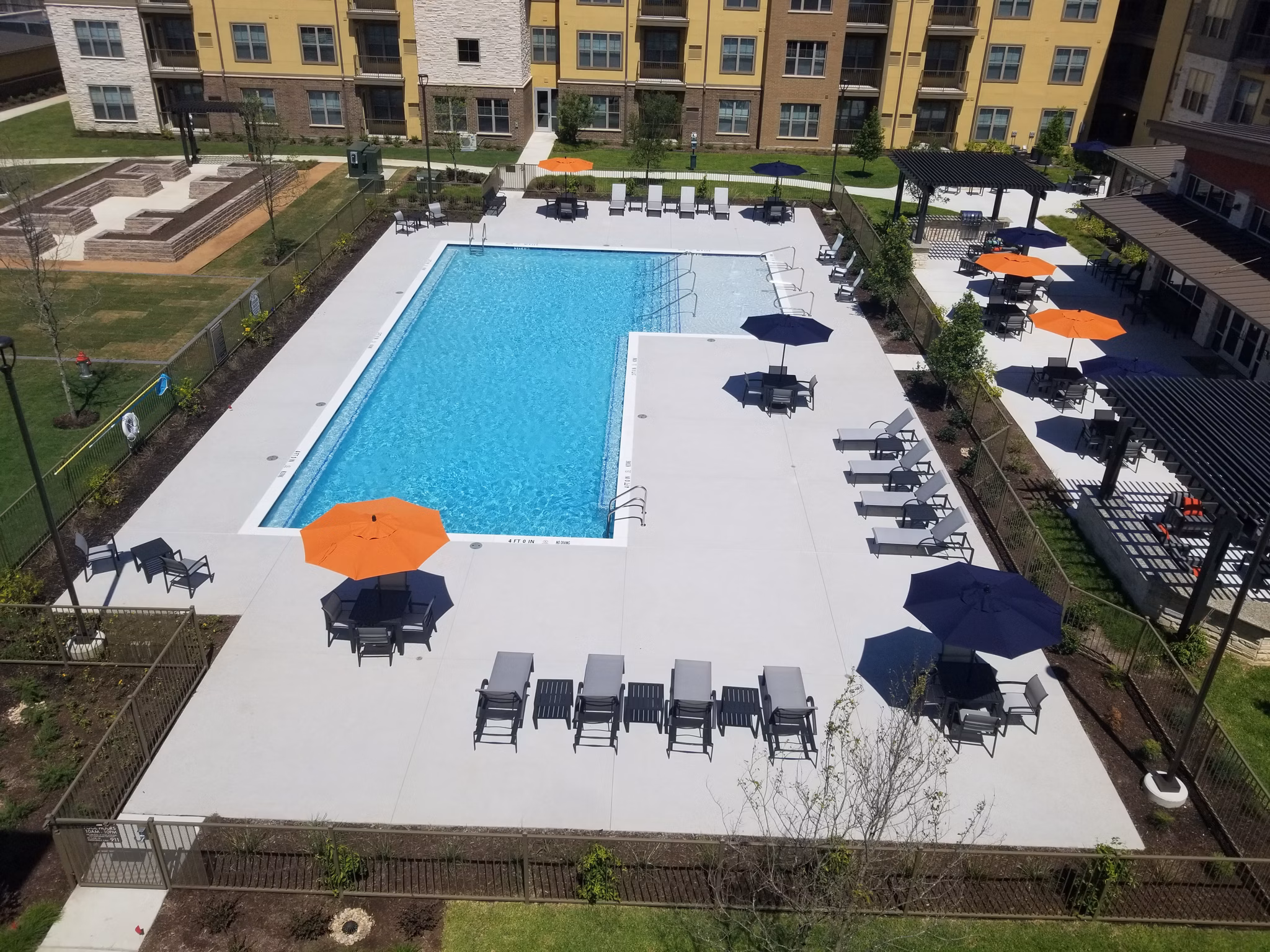 Resort-style pool with sun loungers and lush landscaping at The Orchards at Arlington Highlands Apartments