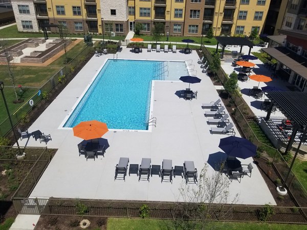 Resort-style pool with sun loungers and lush landscaping at The Orchards at Arlington Highlands Apartments