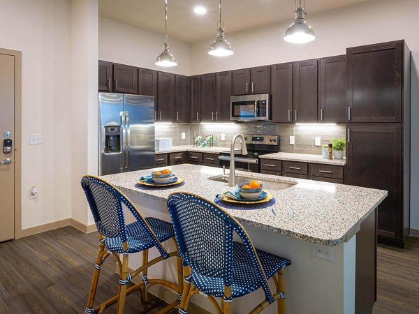 Modern kitchen featuring granite countertops and stainless steel appliances at The Orchards at Market Plaza Apartments
