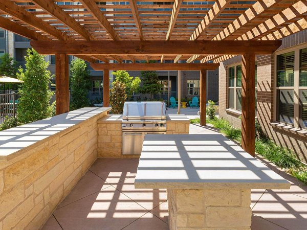 Outdoor grill area at The Orchards at Market Plaza Apartments with modern seating and greenery, perfect for dining and gatherings