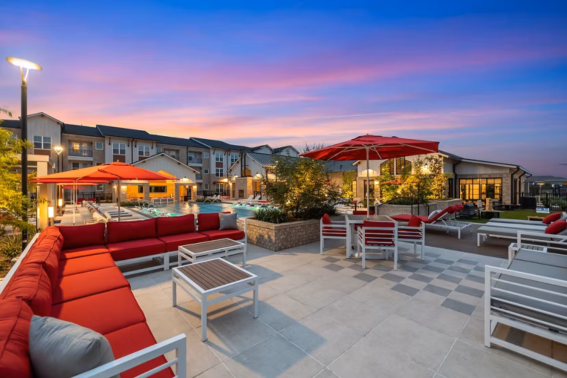 Outdoor patio area with modern seating and lush greenery at Silos Harvest Green Apartments, ideal for relaxation and socializing