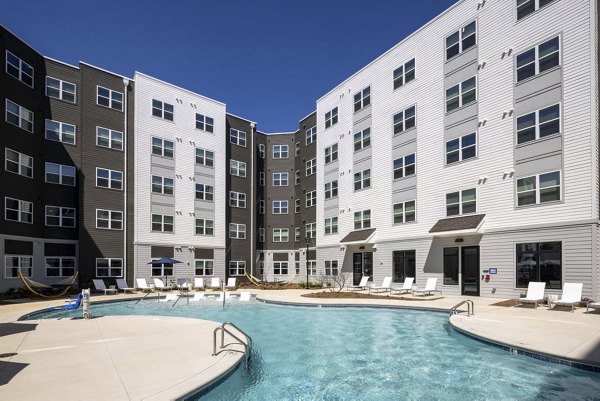 Sunlit outdoor pool at Prose McCullough Station Apartments, featuring lounge chairs and vibrant landscaping