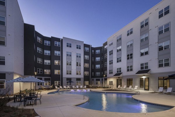 Modern outdoor pool at Prose McCullough Station Apartments with sun loungers and palm trees