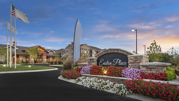 Entrance to Easton Place with landscaped flowers, stone sign, and flags enhancing curb appeal