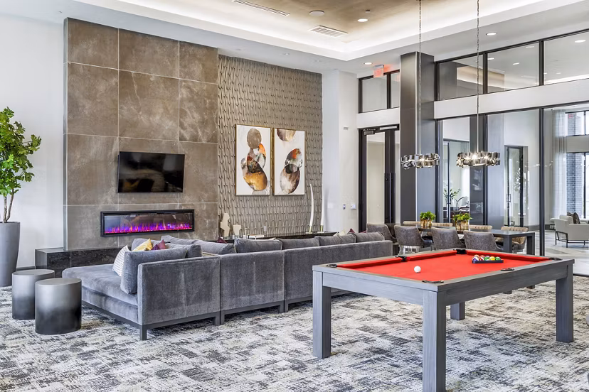 Clubhouse game room with pool table and lounge seating at Avelyn San Marcos Apartments