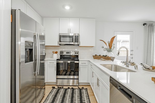 Modern kitchen with stainless steel appliances and granite countertops in Summerwell Wildcat Ranch Home Apartments