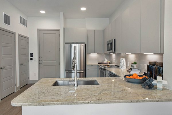 Modern kitchen with stainless steel appliances and quartz countertops in Stadia Med Main Apartments