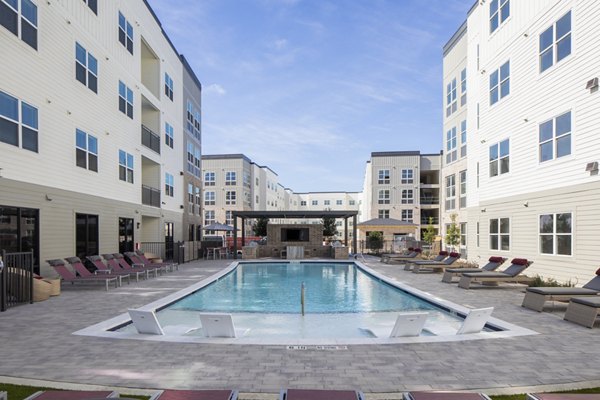 Luxurious pool at Prose KTX Apartments with lounge chairs and umbrellas, ideal for relaxation in a premier living environment