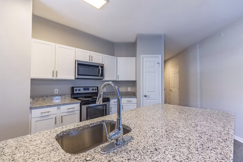 Modern kitchen with stainless steel appliances and quartz countertops in Nav850 Apartments