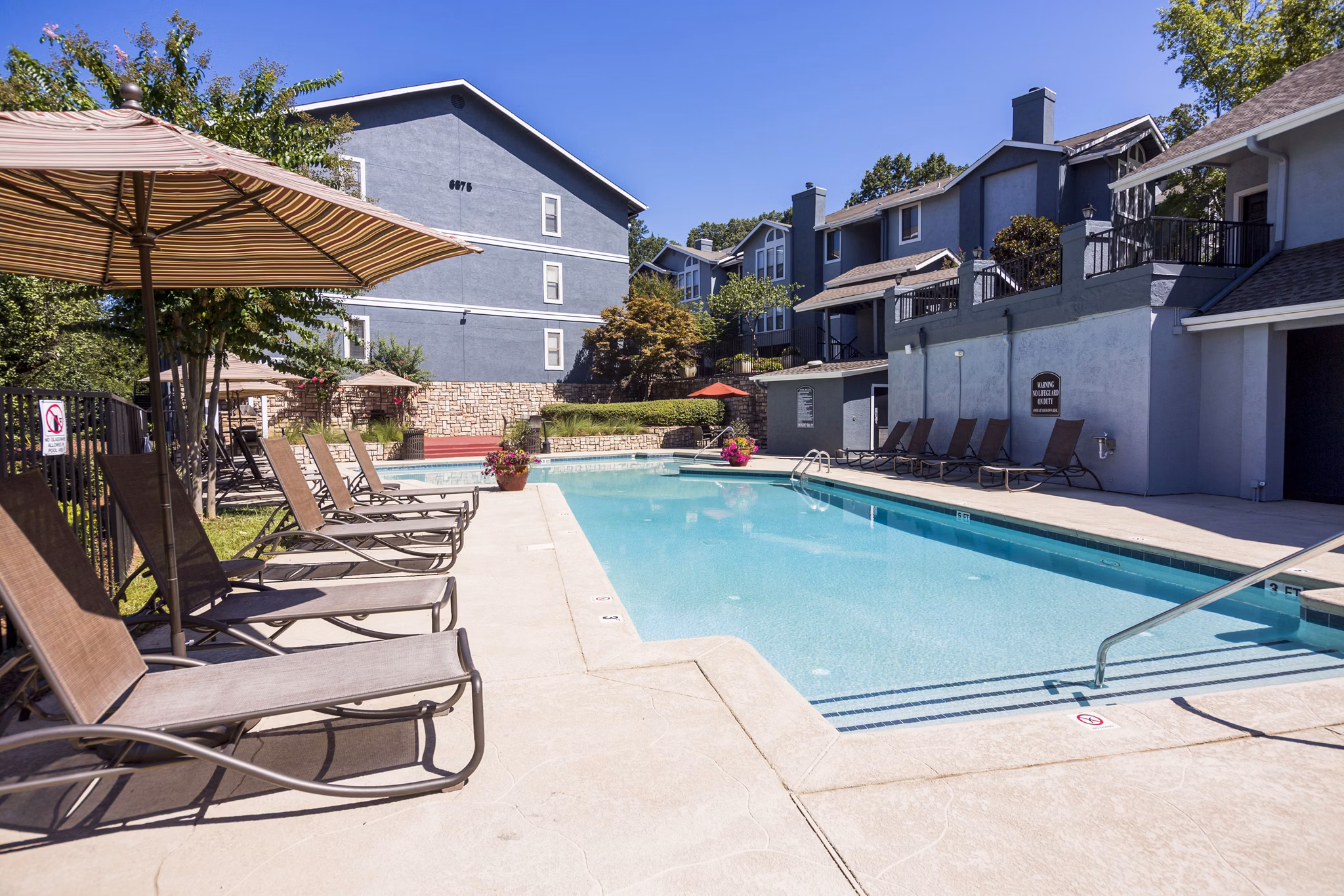 Inviting pool area at Aventura Dunwoody Apartments with relaxing lounge chairs and lush landscaping