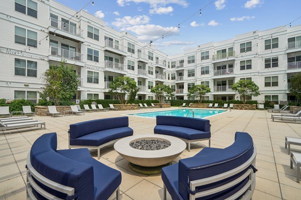 Cozy fire pit on patio next to swimming pool at 75 Tresser Apartments, offering luxury outdoor living spaces