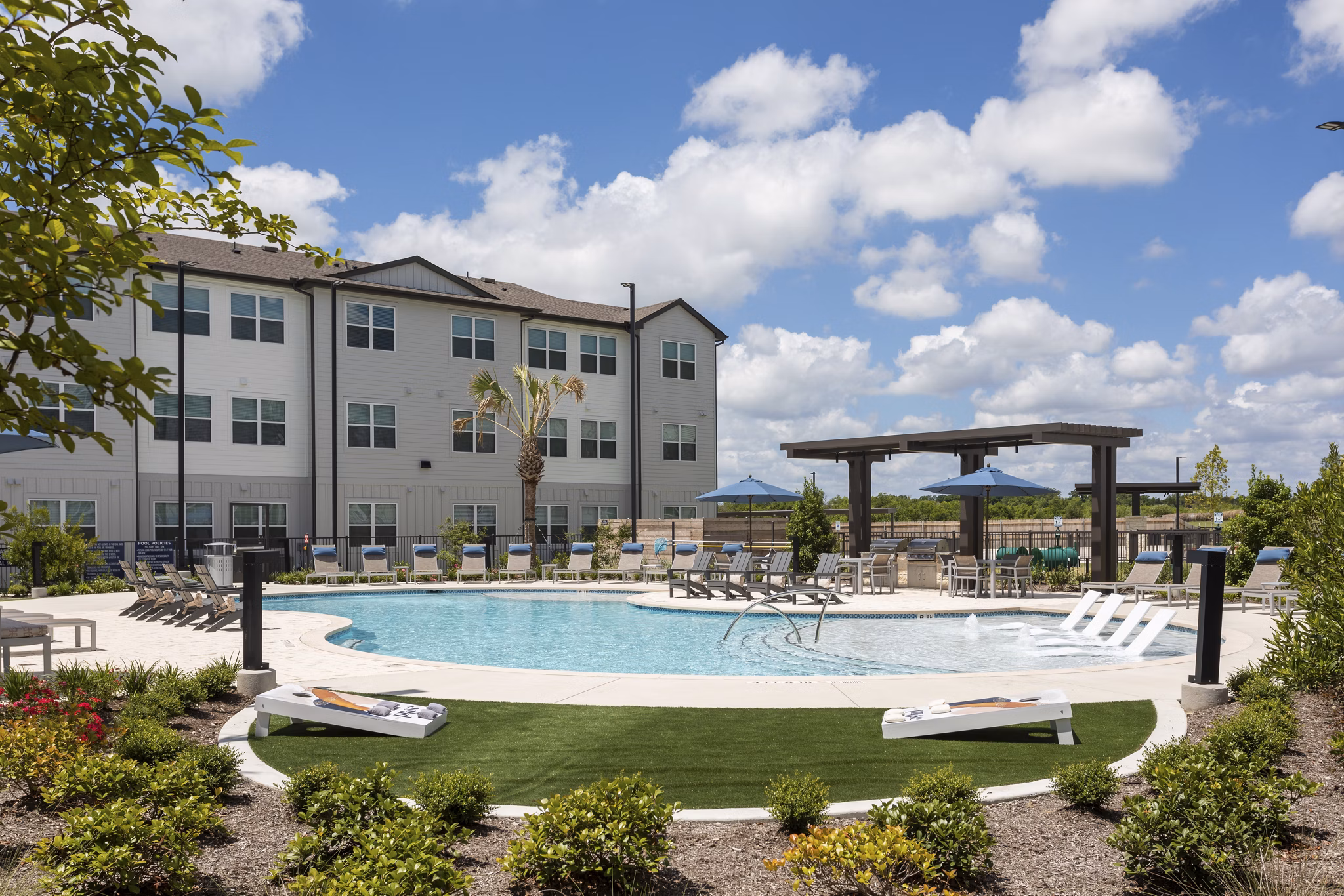 Resort-style pool at Prose Buda Apartments with lounge seating and lush landscaping