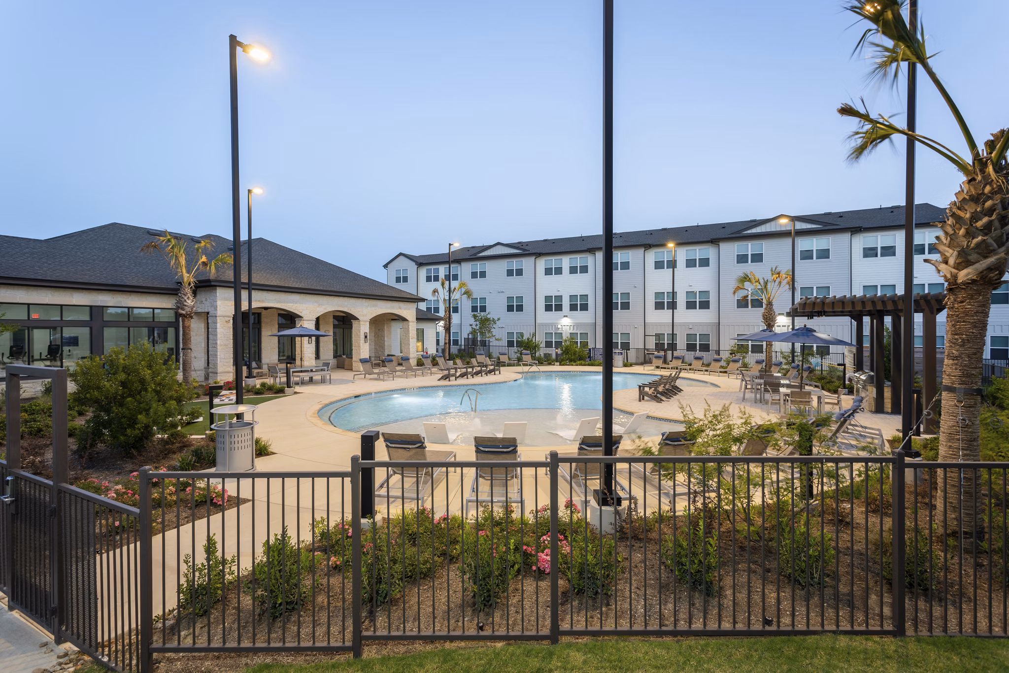Luxurious resort-style pool at Prose Buda Apartments featuring elegant lounge chairs and lush landscaping
