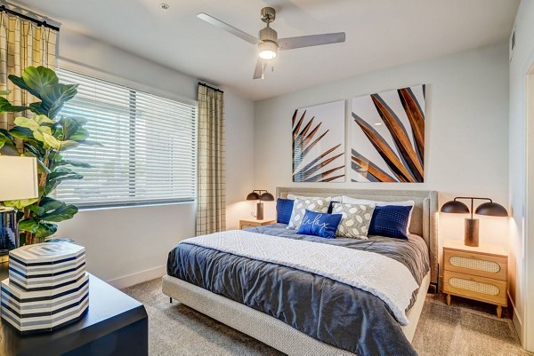 Peaceful bedroom with modern decor and large windows at Encore Novo Apartments, perfect for a luxurious living experience