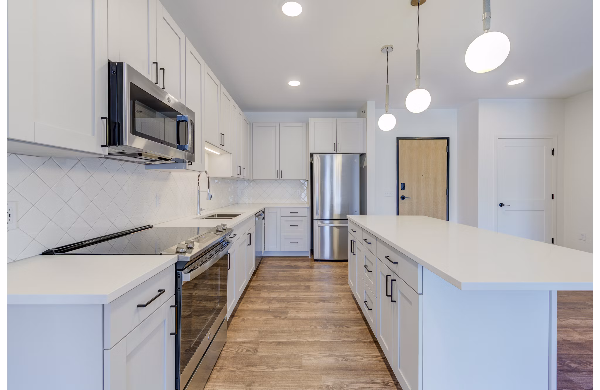 Modern kitchen with stainless steel appliances and marble countertops at The James Apartments