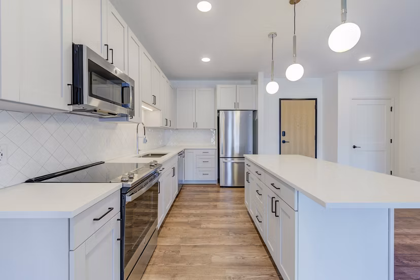 Modern kitchen with stainless steel appliances and marble countertops at The James Apartments