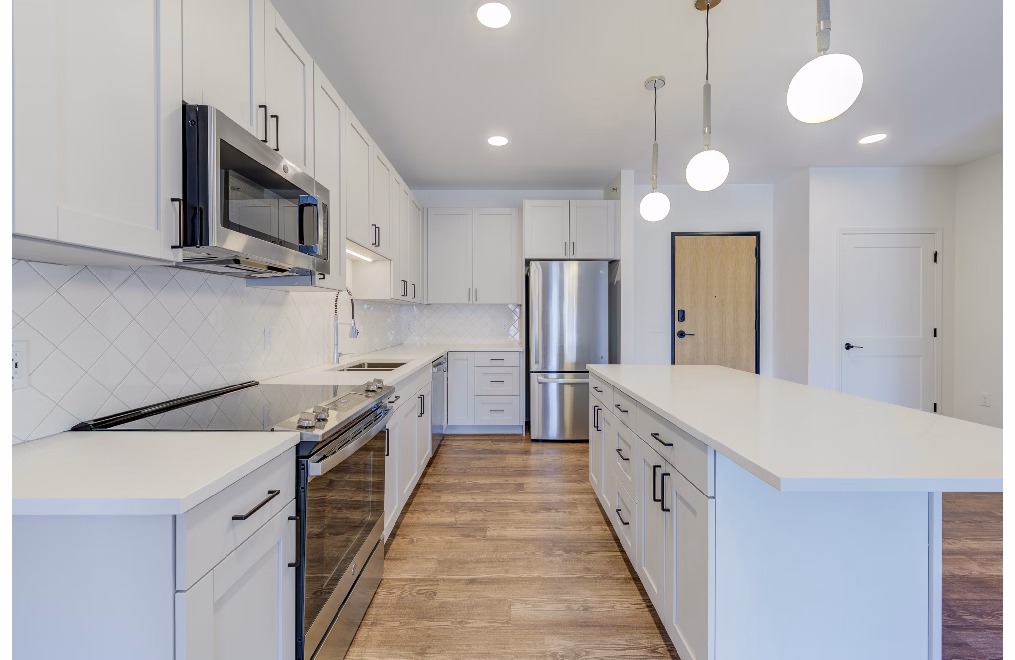 Modern kitchen with stainless steel appliances and marble countertops at The James Apartments