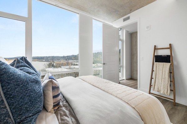 Luxurious bedroom with plush bedding and large windows at Willamette Tower Apartments in Portland, offering city views