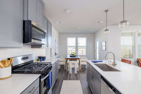 Modern kitchen featuring stainless steel appliances and granite countertops in Caso University Heights Apartments
