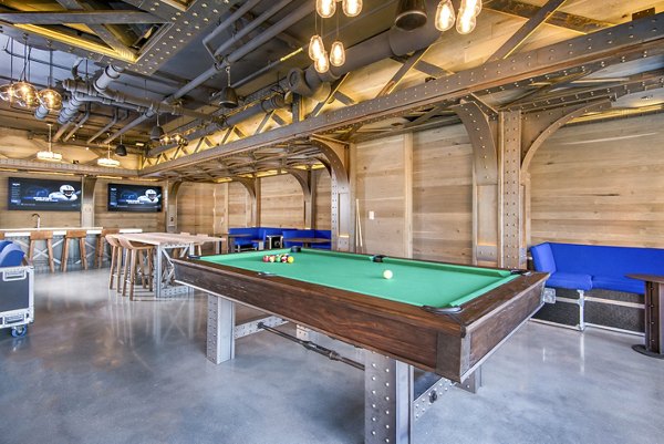 Clubhouse game room with pool table and large TV at Spoke Apartments, perfect for leisure and socializing